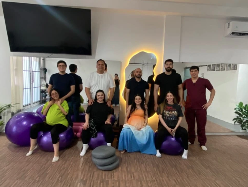 Grupo de mamás y acompañantes en una clase de preparación prenatal de UMaMa con pelotas de pilates